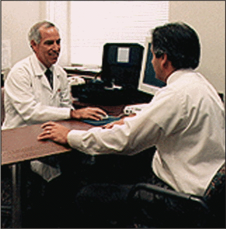 Figure. Dr. David B. Hawkins counsels a patient at his hearing clinic as to which hearing aid is best for his needs.
