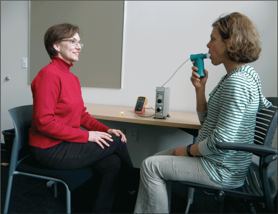 Figure. Dr. Barbara Mathers-Schmidt (left) instructs a patient on using an inspiratory muscle trainer as part of her PVFM treatment.